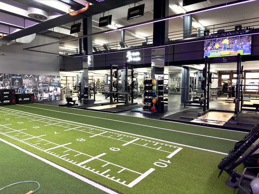Trainingsfläche im FTB Nürnberg mit Kunstrasenbahn, Squat-Racks und Freihantelbereich